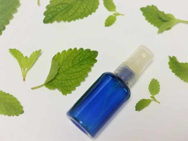 a-blue-glass-spray-bottle-with-mint-leaves-on-a-white-surface