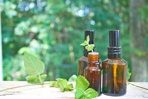 three-amber-glass-bottles-with-fresh-herbs-on-a-wooden-surface-representing-diy-spray-recipes