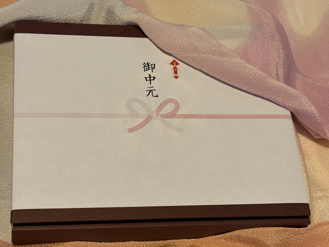 traditional-japanese-summer-gift-ochugen-wrapped-in-white-noshi-paper-with-red-and-white-mizuhiki-knot-on-elegant-fabric